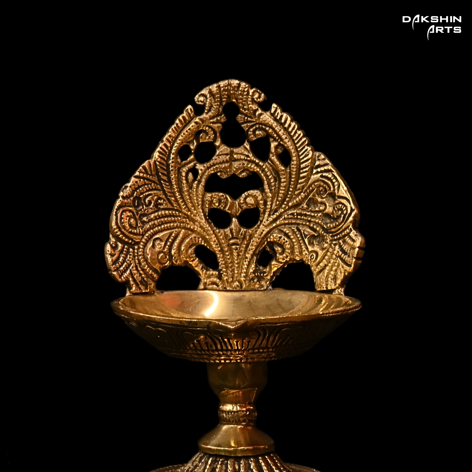 Decorative gold lamp with intricate patterns on a black background, featuring the brand 'Dakshin Arts'.