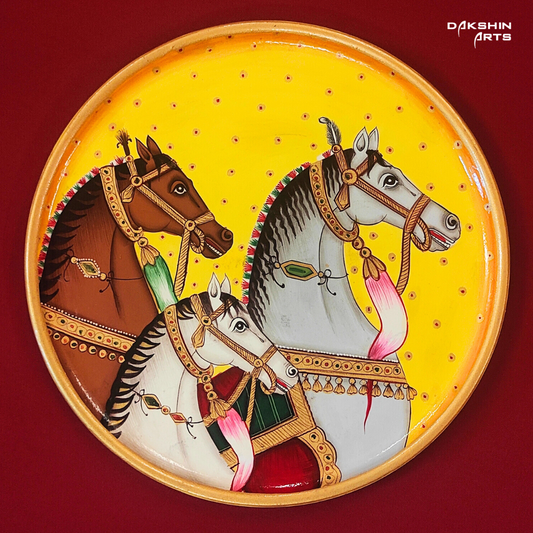 A vibrant painted Pichwai wooden plate features three intricately adorned horses on a bright yellow background - Dakshin Arts