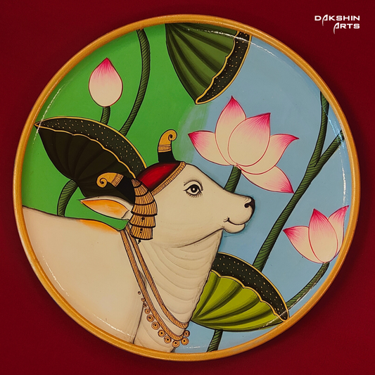 A Pichwai wooden plate with an intricately painted cow surrounded by vibrant lotus flowers and leaves- Dakshin Arts