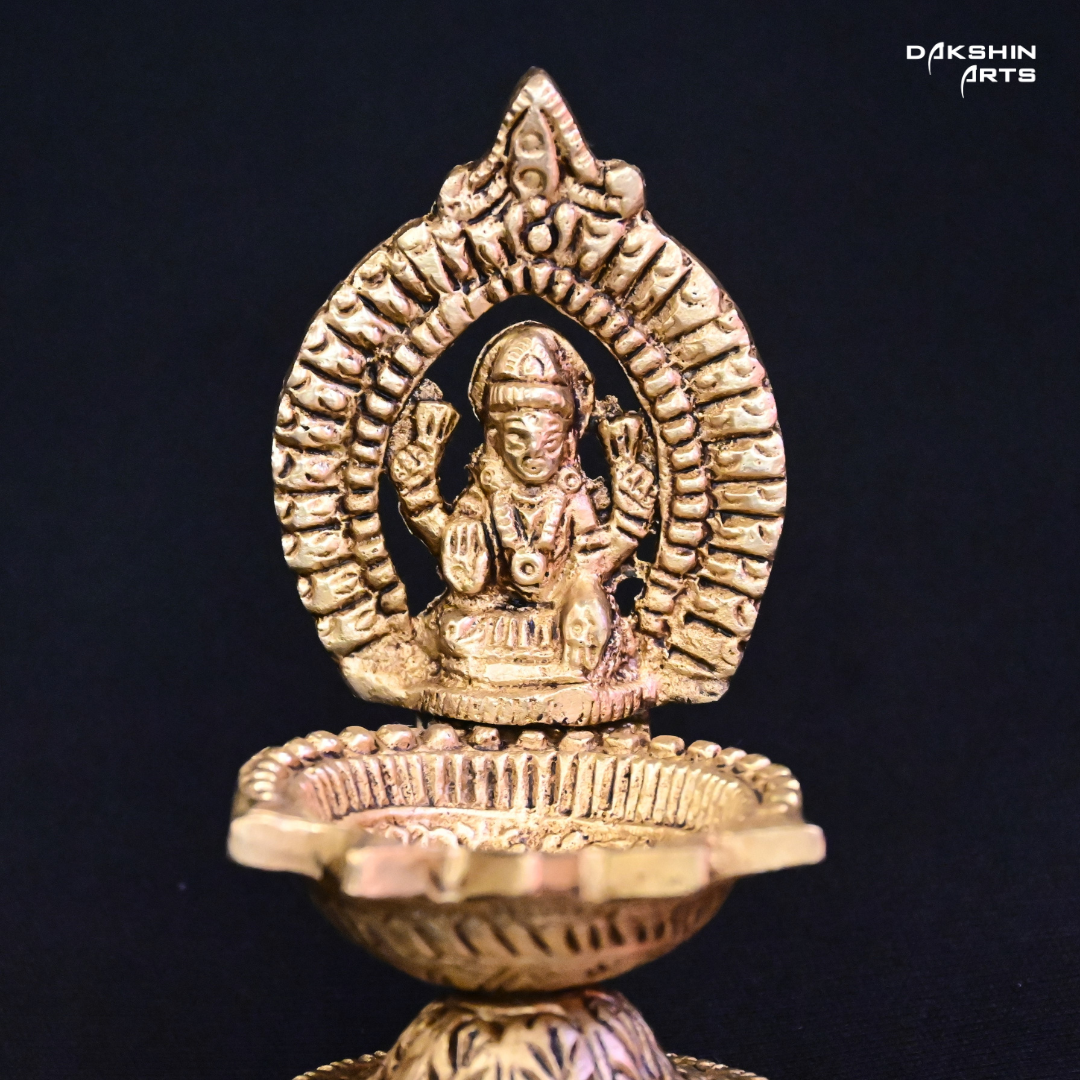 One ornate brass oil lamp with a closeup of intricate carvings of Laxmi - Dakshin Arts