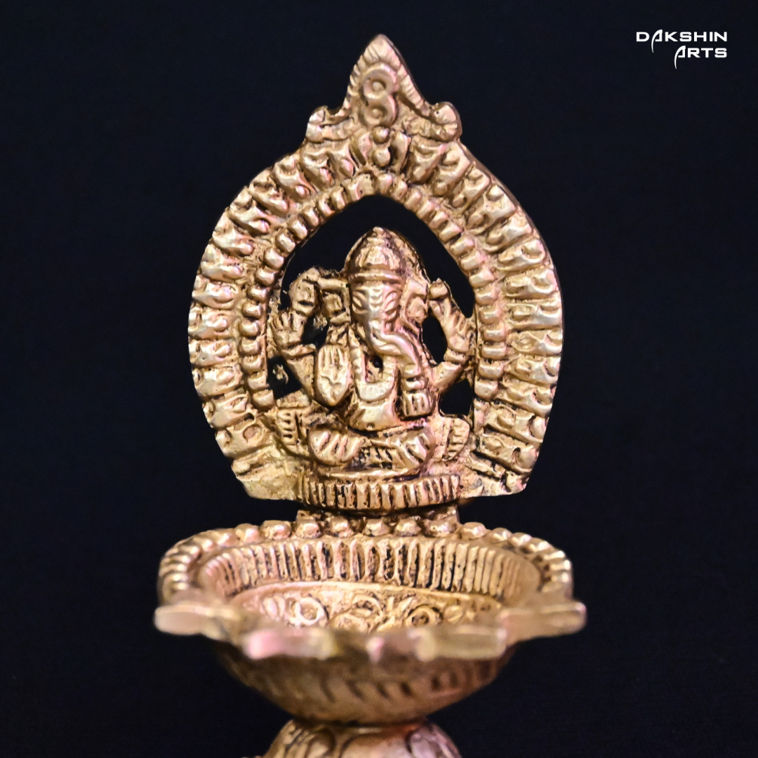 One ornate brass oil lamp with a closeup of intricate carvings of Ganesha- Dakshin Arts