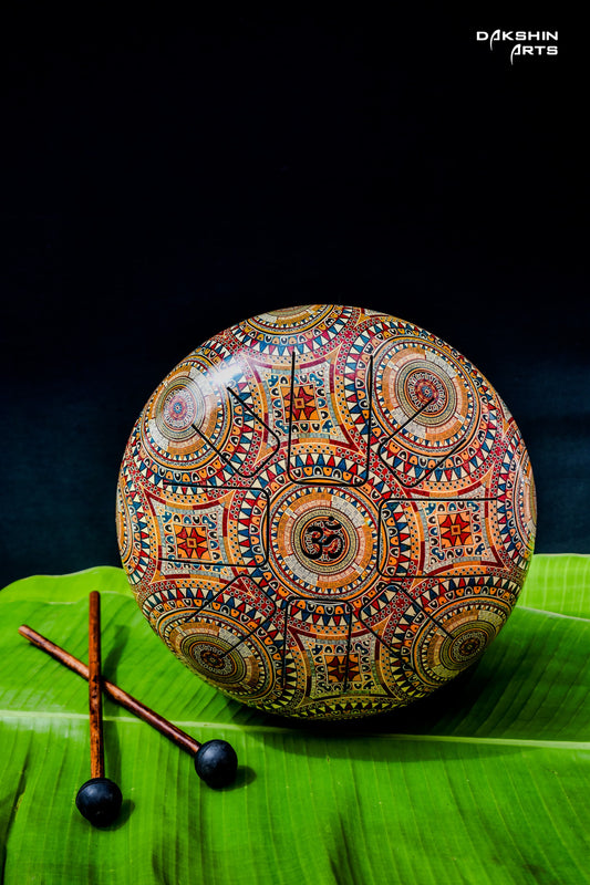 A colorful Hapi drum with intricate mandala patterns. Two wooden mallets lie beside it on the leaf - Dakshin Arts