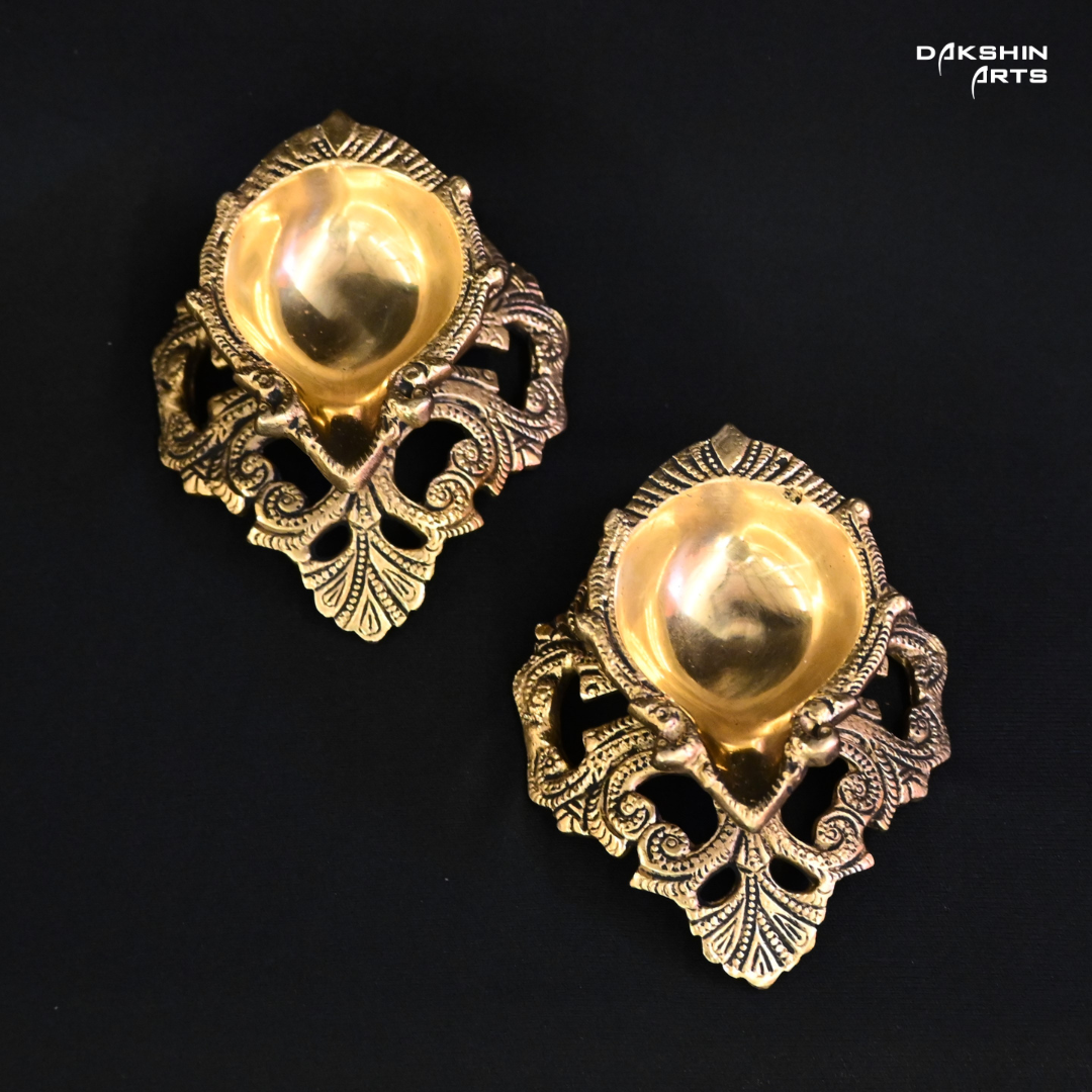 Two ornate brass diyas, intricately designed, showcasing traditional craftsmanship and elegance- Dakshin Arts