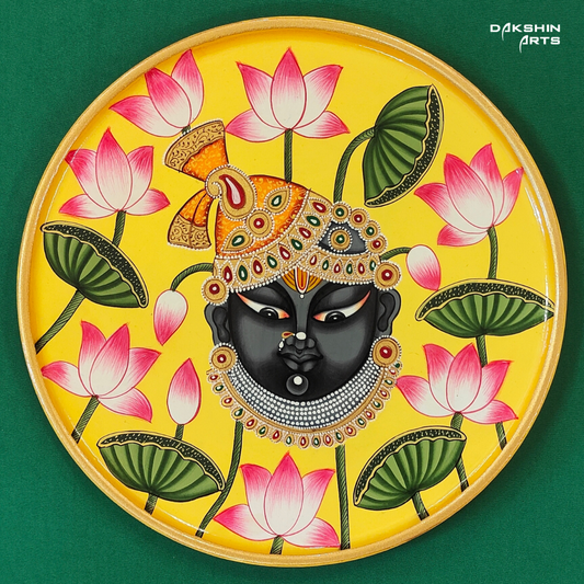 A vibrant Pichwai wooden plate features a Srinathji , surrounded by blooming pink lotuses on a bright yellow background - Dakshin Arts