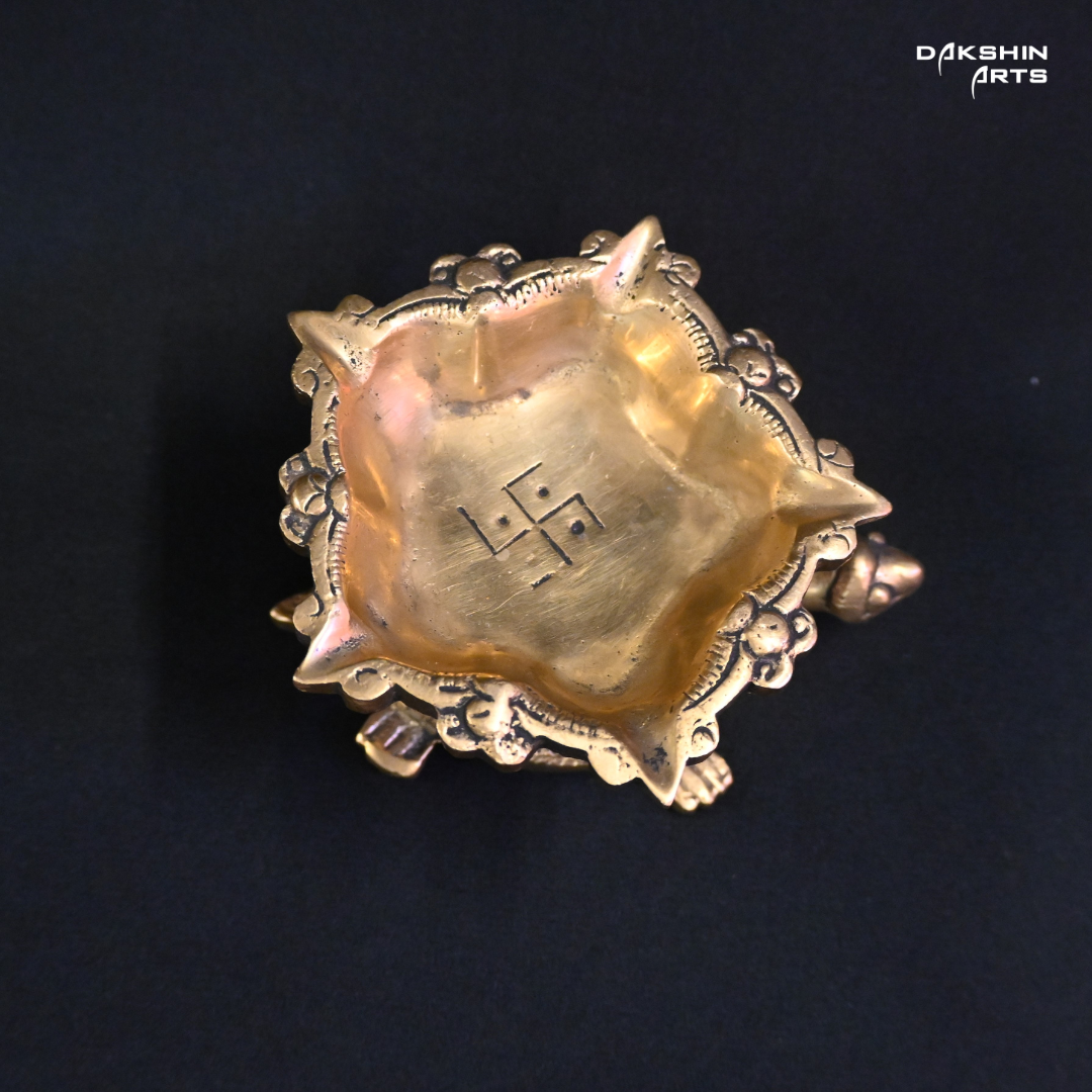 A brass decorative piece in the shape of a turtle with a diya on top.