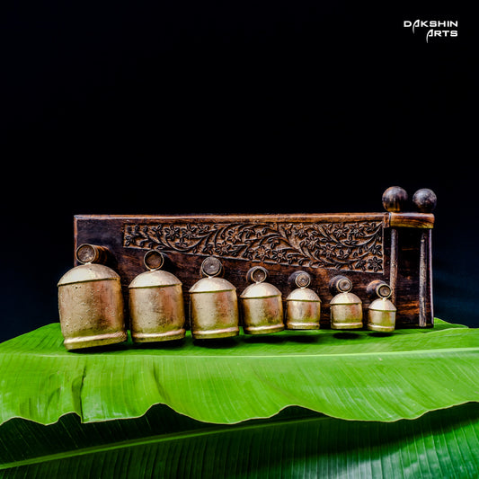 Ornate brass coloured bell like pieces arranged by size on carved wooden stand - Dakshin Arts