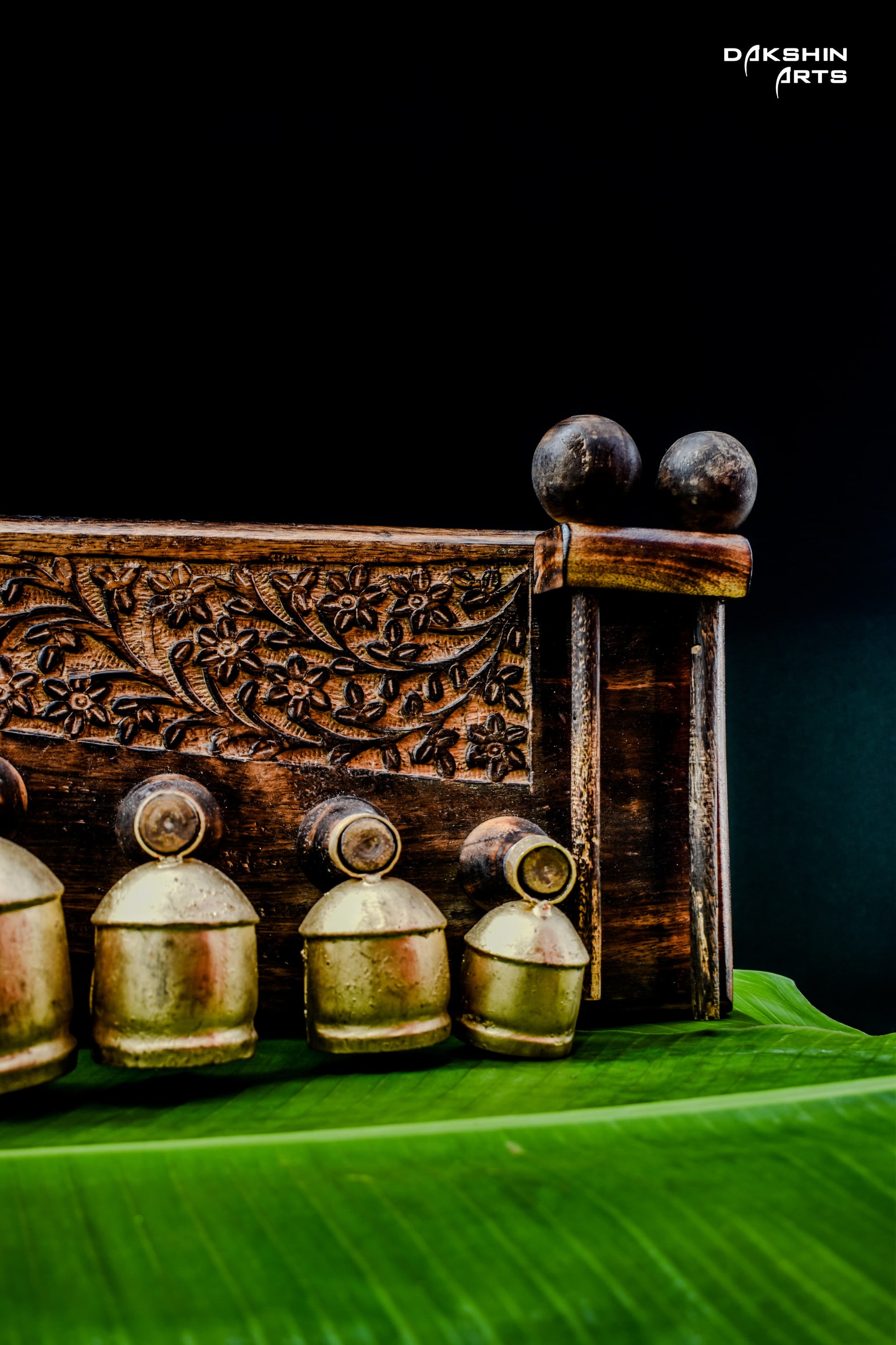 Ornate brass coloured bell like pieces arranged by size on carved wooden stand - Dakshin Arts