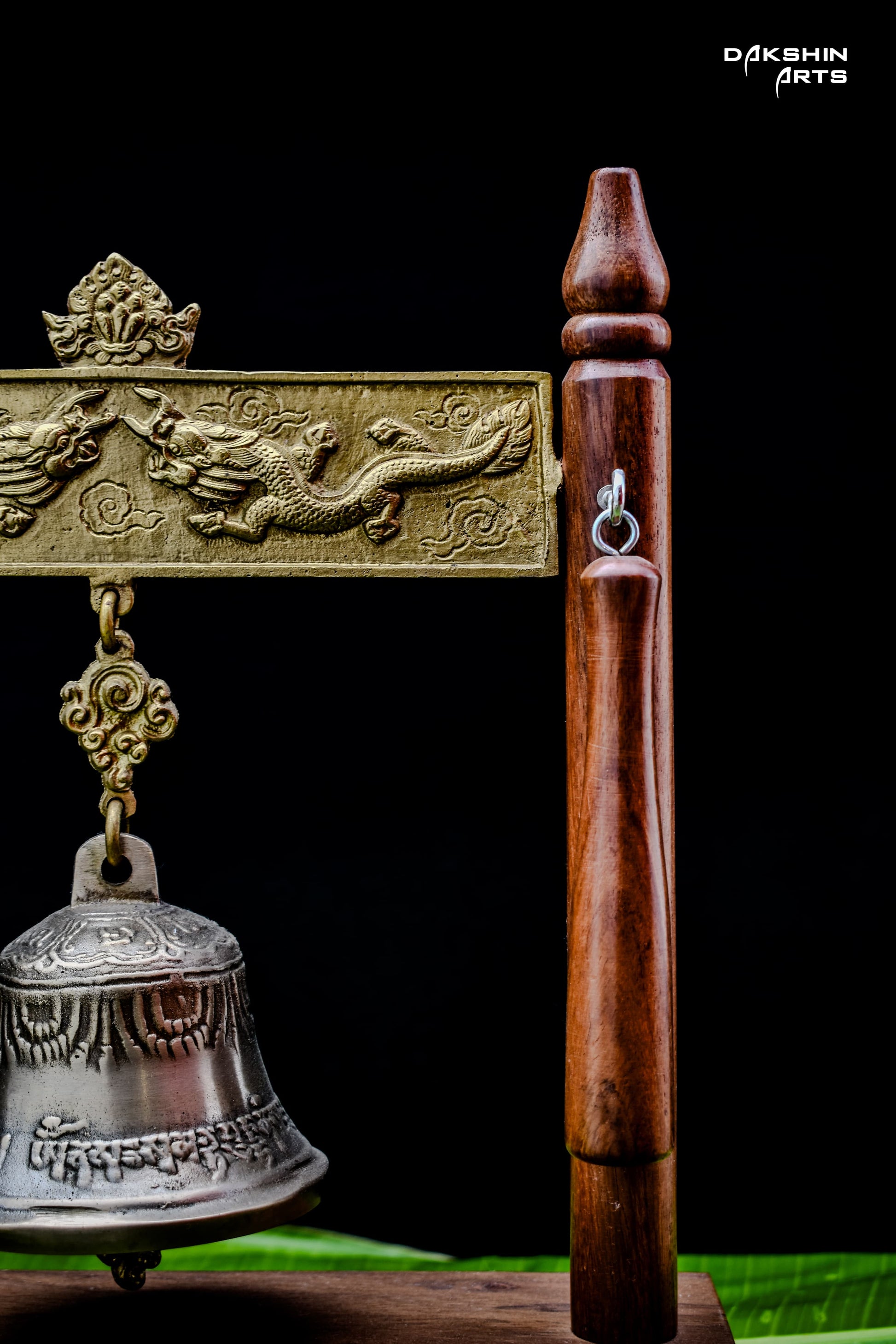 Close-up of the wooden frame with intricate designs from which the bell ishanging- Dakshin Arts