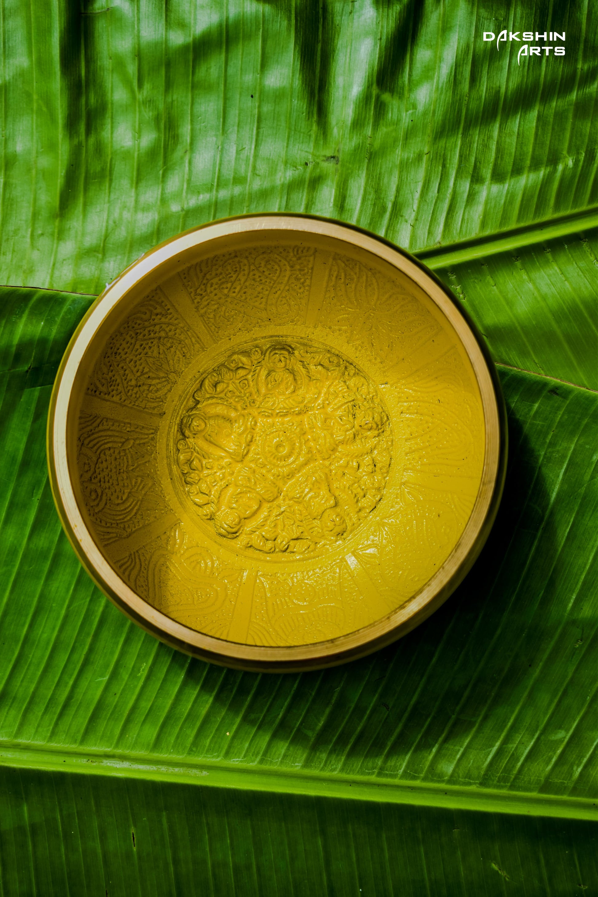 Yellow bowl with script sits atop  green banana leaves - Dakshin Arts